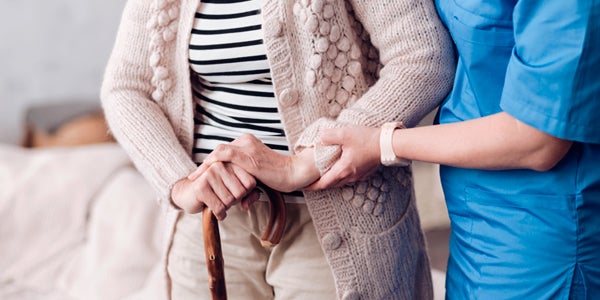 medical assistant helping elderly walk