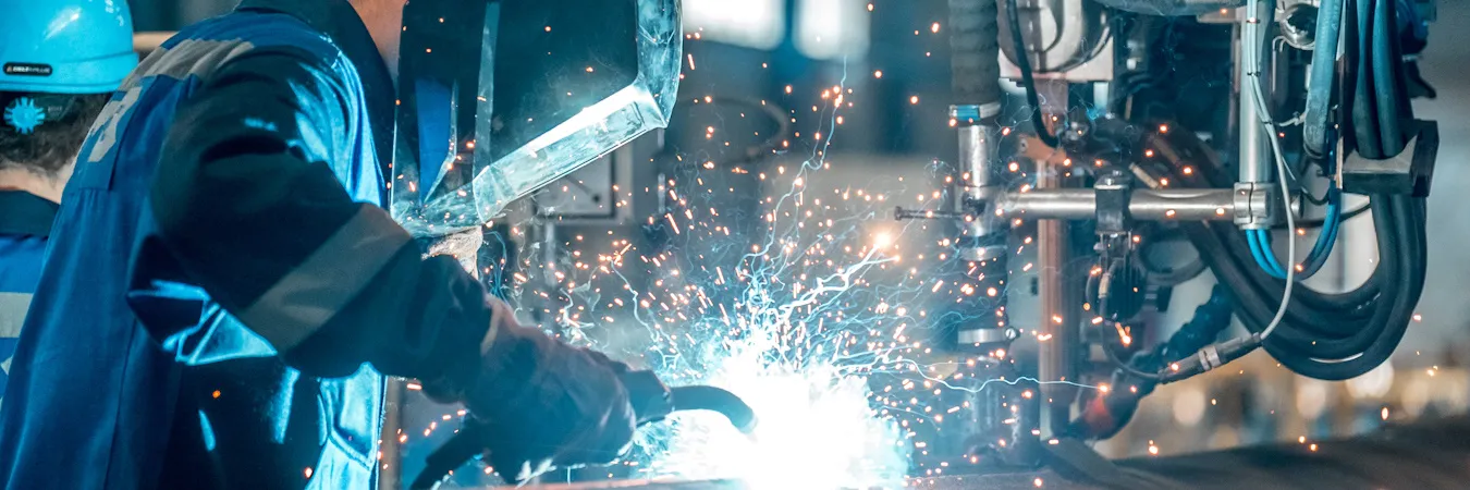 Welder working on piece of equipment